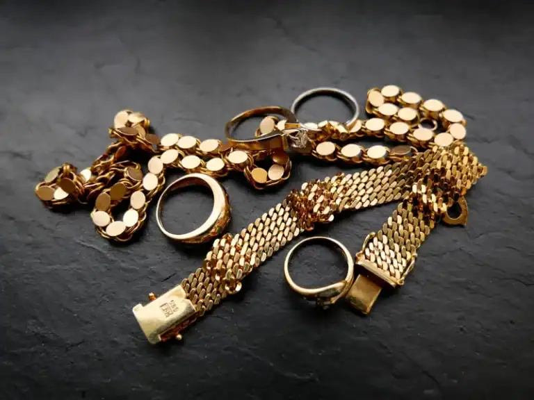 Goldschmuck mit Ringen und Armbändern auf dunklem Hintergrund